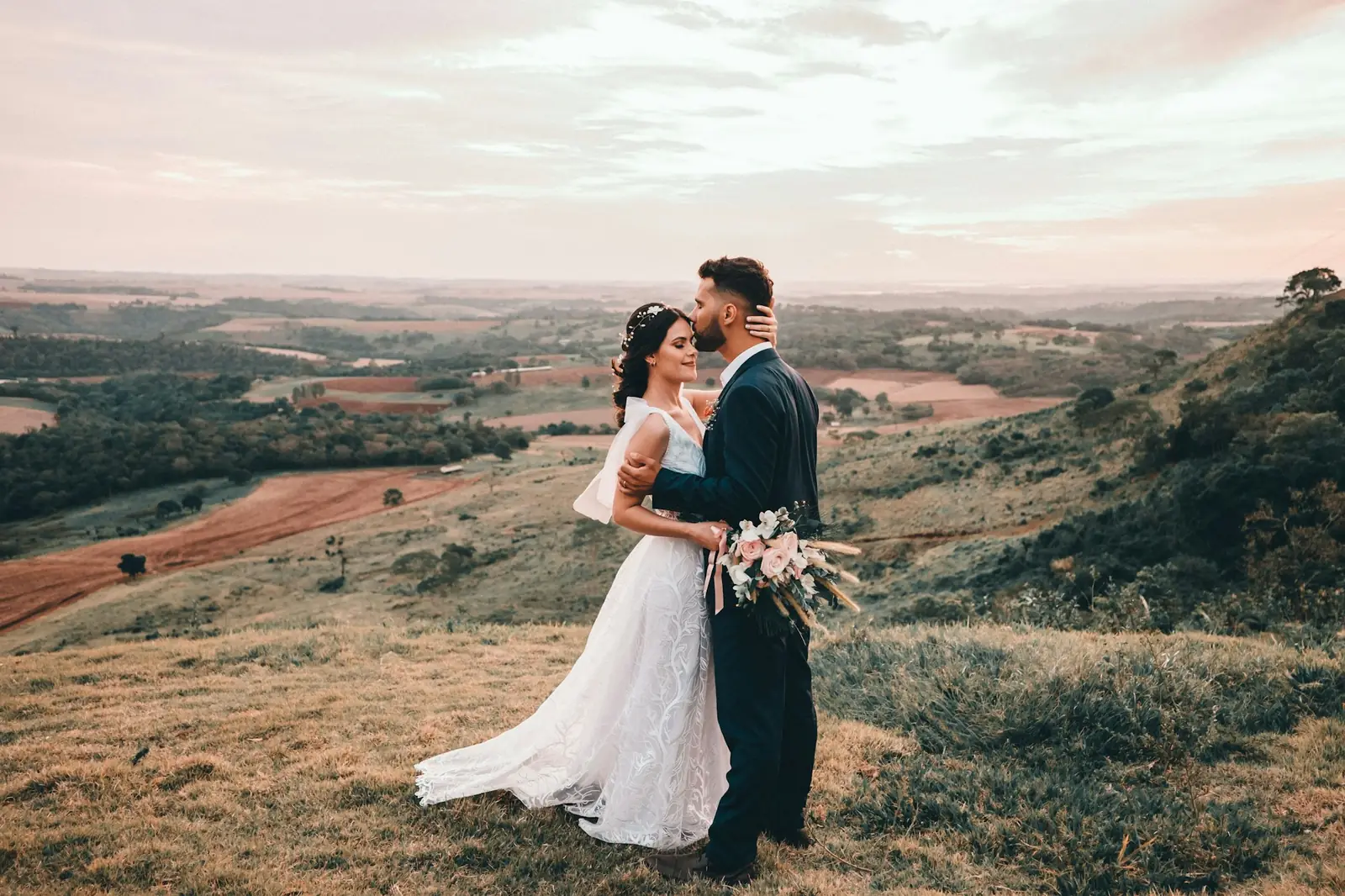 Noivos se beijando no alto de uma colina